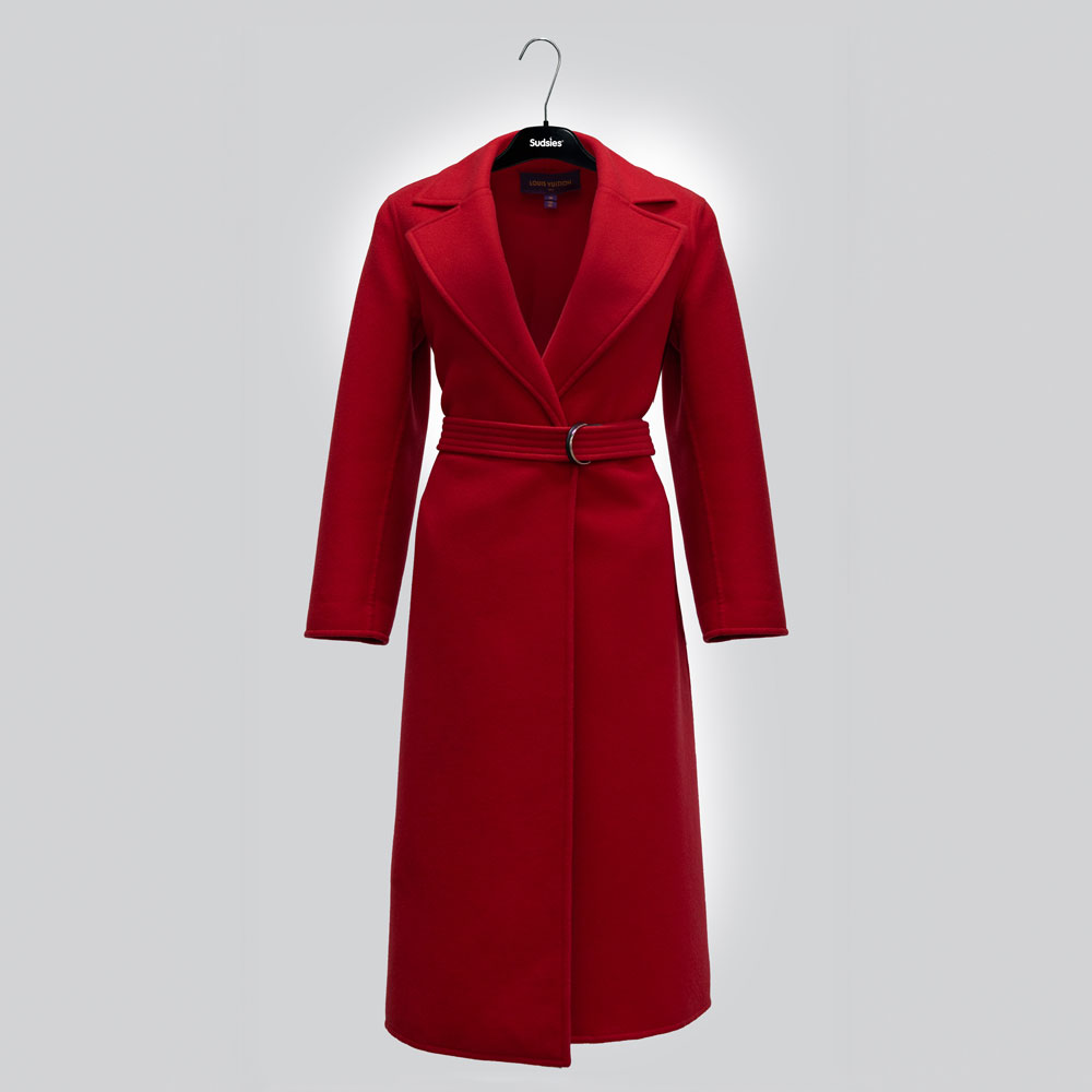 A luxurious red Louis Vuitton trench coat on a Sudsies hanger against a light grey background.